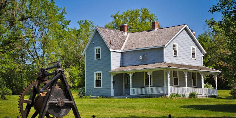 Une maison historique avec une grande véranda et un mécanisme d’écluse en avant-plan