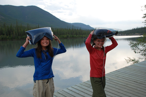 Deux jeunes visiteurs transportent de l'eau jusqu'à leur camp dans la réserve de parc national du Canada Nahanni.