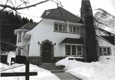 Façade avant de la résidence du directeur, qui montre le mariage du stuc à fini grossier avec les boiseries et la pierre, vers 1991. © Agence Parcs Canada / Parks Canada Agency, ca./vers 1991.