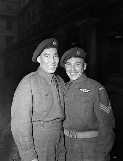 Le Sergent Tommy Prince (à droite), M.M. Médaille militaire, 1er bataillon de parachutistes canadiens, en compagnie de son frère, le Soldat Morris Prince, à une cérémonie d'investiture au palais de Buckingham (© Christopher J. Woods / Canada. Dept. of National Defence / Library and Archives Canada // Ministère de la Défense nationale / Bibliothèque et Archives Canada / PA-142289)