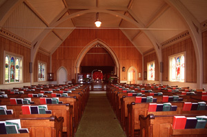 View of the interior of Tryon United Church, showing its interpretation of Gothic forms and detailing in wood, as seen in its faux-buttresses and its tripled Gothic arch stained glass windows, 1995. © Parks Canada Agency / Agence Parcs Canada, J. Butterill, 1995.