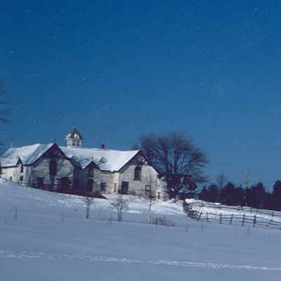 View of the south façade of the Stable, showing the central ventilation cupola with its louvred sides pyramidal roof and miniature gables, 1991. © Parks Canada Agency / Agence Parcs Canada, E. Tumark, 1991.