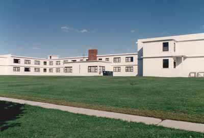 View of the rear façade of Building B-39, showing the wrap-around continuity of the belt courses, 1993. © Parks Canada Agency / Agence Parcs Canada, 1993.