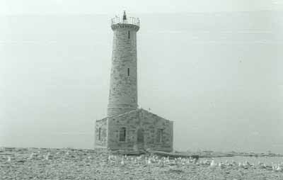 General view of the Lighthouse at Mohawk Island, showing the building’s tall profile, cylindrical form and the integration of the simple residence, ca. 1980. © Department of the Environment / Ministère de l'Environnement, ca./vers 1980.