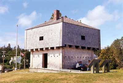 Corner view of St. Andrews Blockhouse, showing the squat square profile, pyramidal roof, entrance and the artillery gunports, machicolation loopholes and musketry holes, 1998. © Parks Canada Agency/Agence Parcs Canada, 1998.