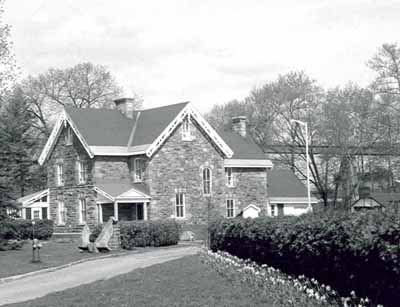 View of the exterior of the Superintendent's House, showing the two-and-a-half-storey massing, and the gable roof with chimneys, 1985. © Parks Canada Agency / Agence Parcs Canada, 1985.