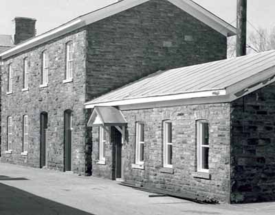 View of the exterior of the Workshop, showing the exterior walls of random coursed red sandstone, 1985. (© Parks Canada Agency / Agence Parcs Canada, 1985.)