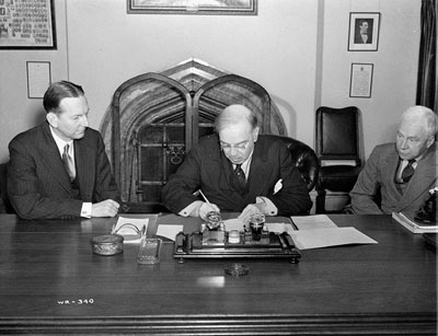 Signing of the Canada-United States agreement on the construction and maintenance of the Alaska Highway. © Frank C. Tyrell / National Film Board of Canada. Phototheque / Library and Archives Canada / PA-130488