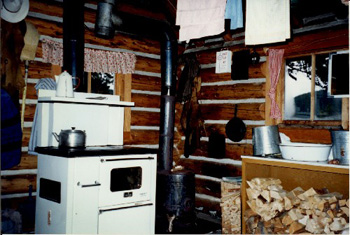 Interior view of the Middle Forks Warden Patrol Cabin, showing the interior objects and its walls constructed of peeled logs, 1997. © Parks Canada Agency / Agence Parcs Canada,  1997.