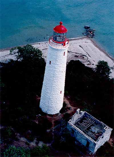 Aerial view of the Chantry Island Lighthouse showing its tall, round, slightly tapered form corbelled at the top to form a gallery and base for the lantern, 1990. © Canadian Coast Guard / Garde côtière canadienne, 1990.