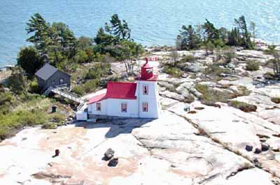 General view of Brebeuf Island Front Range Light Tower, showing its position on a flat bare rock surface. (© Parks Canada Agency/ Agence Parcs Canada, Fisheries and Oceans Canada/ Pêches et Océans Canada)