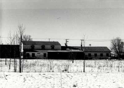 View of the Woodworking Shop, showing the exterior form of the building, which speaks to the transitory nature of many of the activities it accommodated and its workshop function, 1989. © Agence Parcs Canada / Parks Canada Agency, 1989.