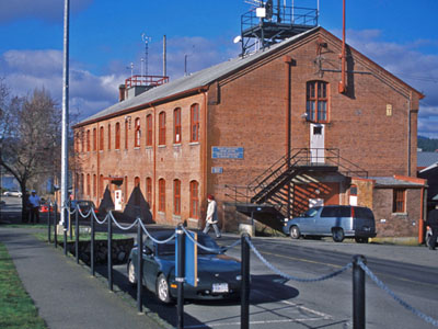 General view of Building D77 Former Ordnance Stores, showing the symmetrical massing of this two-storey, rectangular, gable-roofed building. © Parks Canada Agency / Agence Parcs Canada, Ian Doull.