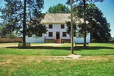 General view of the front facade of the Big House showing its two-storey rectangular structure that is five bays in length and three bays in width,
with a hipped roof and front verandah, 2002. © Parks Canada Agency / Agence Parcs Canada, M. Trepanier, 2002.