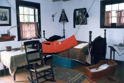 Interior view of Louis Riel House, showing an interpretation of the house in mourning in 1886, 1999. © Parks Canada Agency / Agence Parcs Canada, 1999.