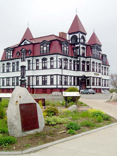 General view of the former Lunenburg Academy, showing the mansard roof in the French Empire style with segmental dormer windows, massive central chimney, and the three projecting towers with pyramidal roofs. (© Parks Canada | Parcs Canada)