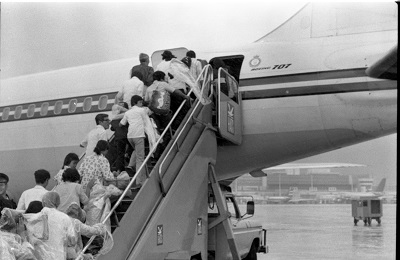 Refugees board first flight of CF707 Hong Kong to Canada, 1979. Photograph attributed to MCpl Bryantowich. (© Canada.Department of National Defence / Library and Archives Canada | Canada. Ministère de la Défense nationale / Bibliothèque et Archives Canada / e999901766-u)