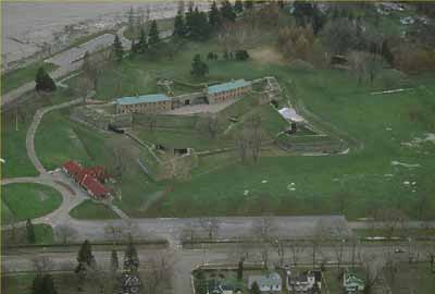 Aerial view of Fort Erie, showing its setting on a flat grassed parcel of land overlooking Lake Erie at the mouth of the Niagara River, 1991. © Parks Canada Agency / Agence Parcs Canada, 1991.