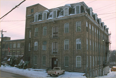 Exterior photo showing massing of 4 storey manufacturing building © Parks Canada/Parcs Canada, 1991