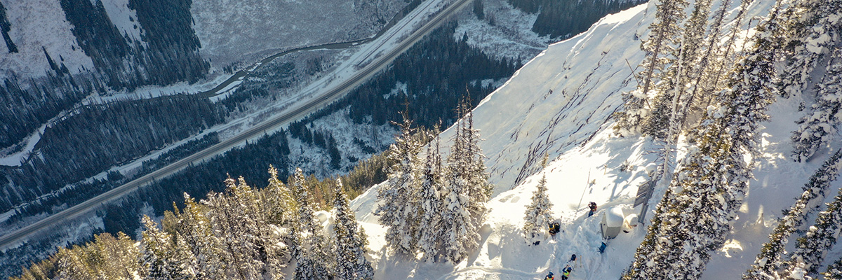 Overhead photo of a snowy mountain peak with a highway far below in the valley